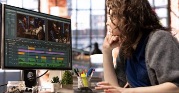 Focused editor woman works on video montage in a creative software at agency office, digital media. Filmmaker using dual monitors to edit footage and create content, post production.