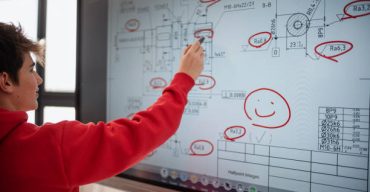 A college student explaining some ideas on a touch TV in classroom.